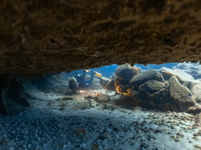 Plongeur explorant un récif rocheux sous une formation calcaire