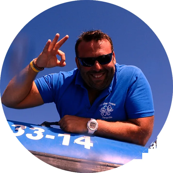 Homme souriant fait un signe de la main devant un bateau bleu