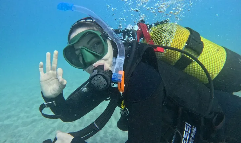 Plongeur souriant faisant un signe de la main sous l'eau