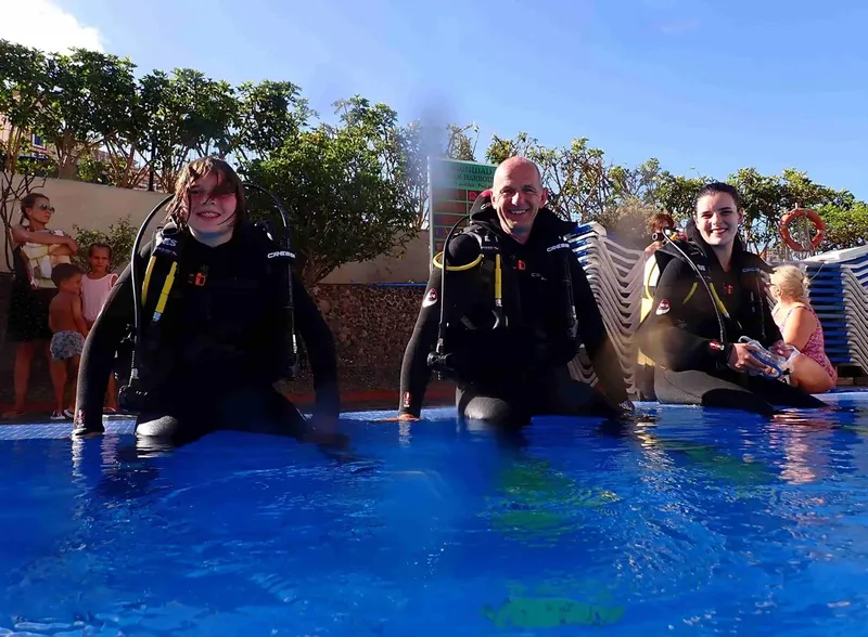 Trois personnes en combinaison de plongée dans une piscine bleue