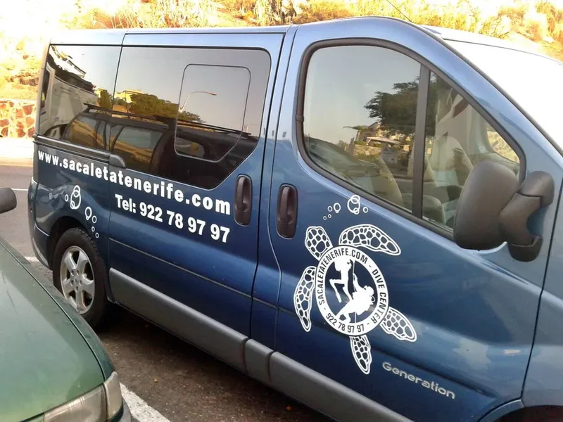 Fourgon bleu avec logo de centre de plongée et coordonnées