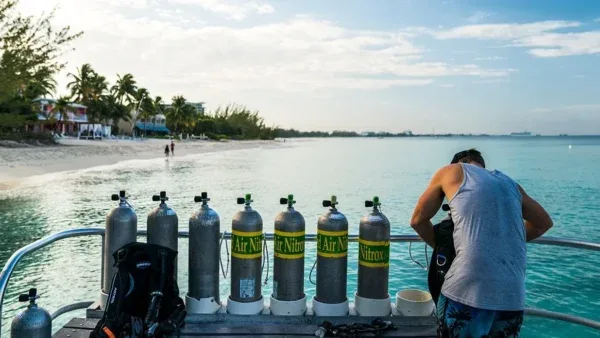 Bouteilles de plongée et personne préparant son équipement sur un bateau