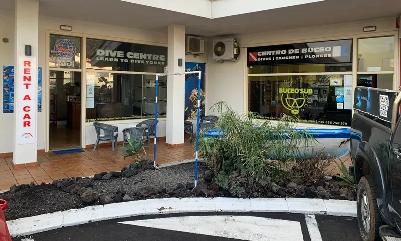Façade d'un centre de plongée avec enseigne et véhicules devant