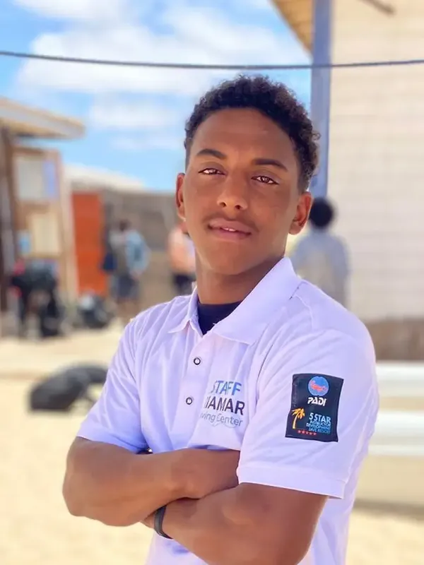 Jeune homme souriant, portant un polo avec logos de plongée