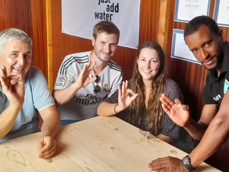 Quatre personnes souriantes font le signe OK à l'intérieur
