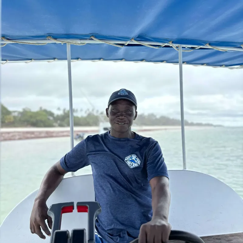 Homme souriant portant un t-shirt et une casquette sur un bateau