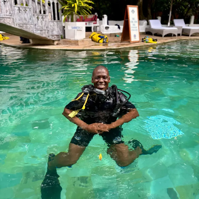 Plongeur souriant dans l'eau avec son équipement complet et un environnement tropical