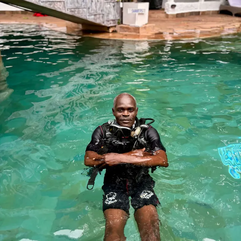 Plongeur en combinaison, masque et détendeur dans une piscine turquoise