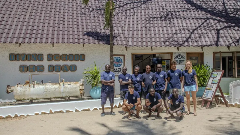 Equipe du centre de plongée posant devant le bâtiment et le compresseur