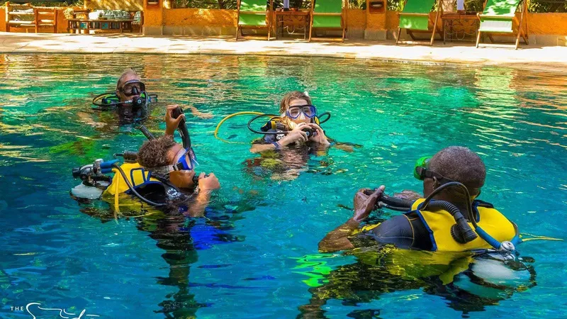 Quatre plongeurs s'entraînent en piscine avec leur équipement complet