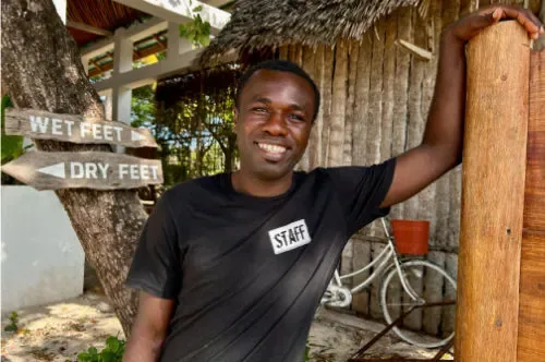 Un homme souriant adossé à un poteau en bois avec un vélo