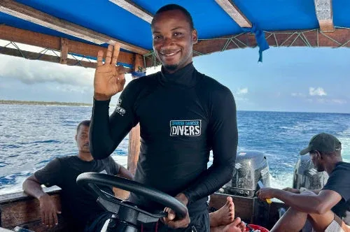 Trois hommes souriants sur un bateau de plongée en mer