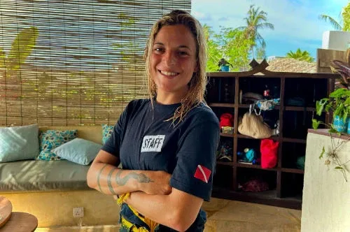 Femme souriante, bras croisés, portant un t-shirt avec l'inscription STAFF