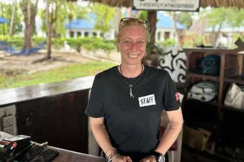 Employée souriante derrière un comptoir dans un centre de plongée
