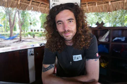 Portrait d'un homme aux cheveux longs devant un comptoir en bois