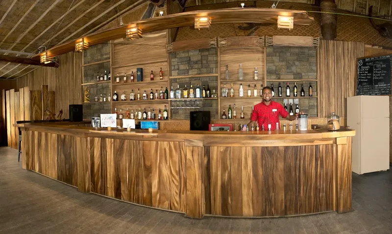 Un bar en bois avec un employé souriant derrière le comptoir