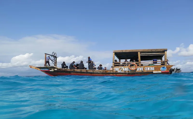 Bateau de plongée avec des passagers, mer bleue et ciel nuageux