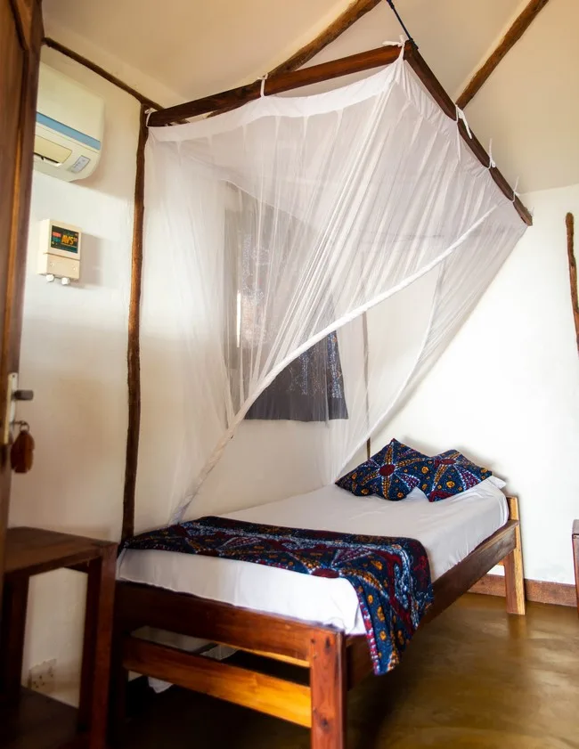 Chambre simple avec moustiquaire, climatiseur et décoration locale