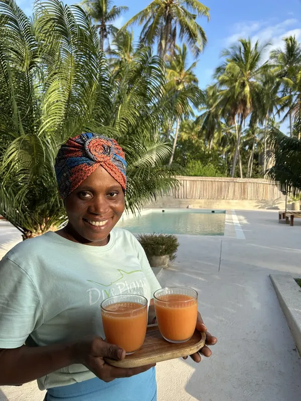 Femme souriante tenant un plateau avec deux verres de jus d'orange