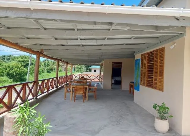 Terrasse couverte avec tables, chaises et végétation tropicale environnante