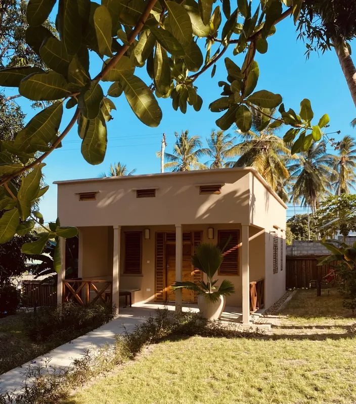 Petite construction beige avec un toit plat et de la végétation tropicale