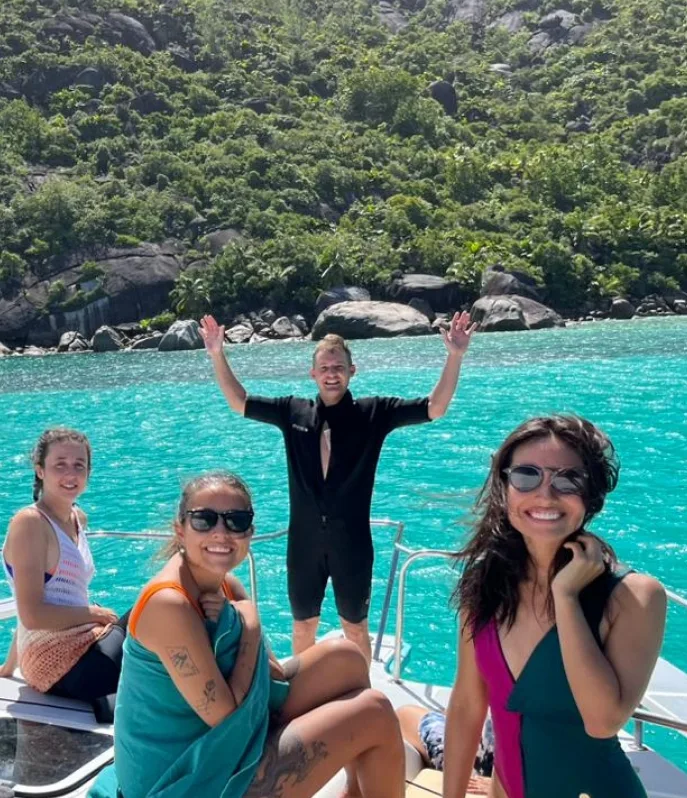 Quatre personnes souriantes sur un bateau en mer turquoise