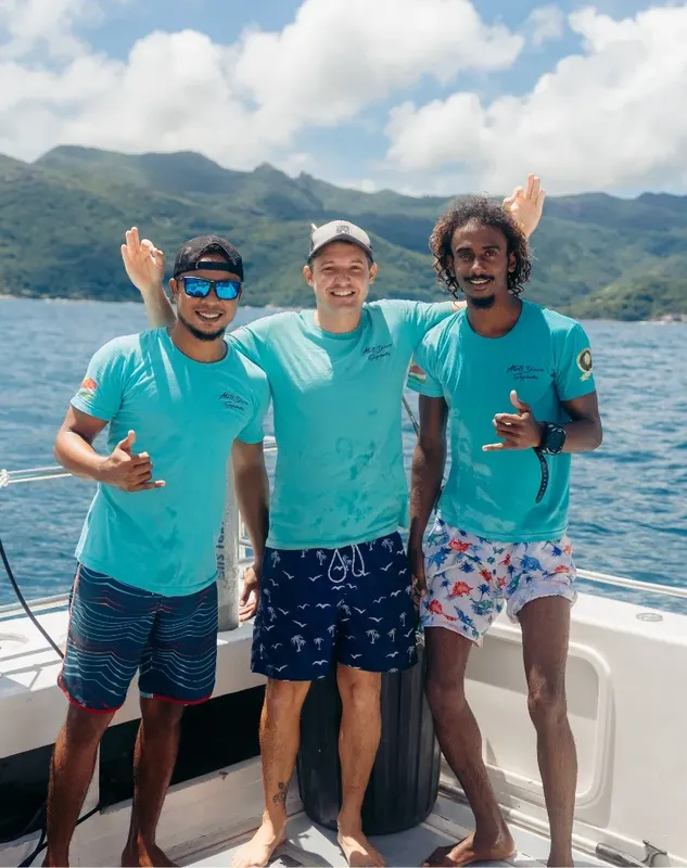 Trois jeunes hommes souriants sur un bateau en mer