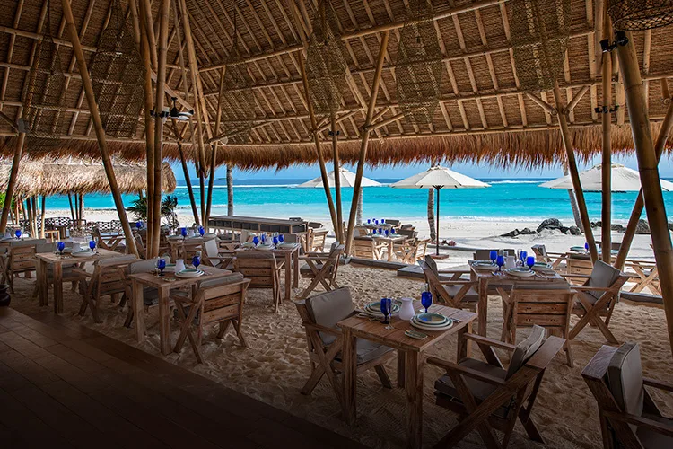 Restaurant de plage avec tables en bois et vue sur mer turquoise