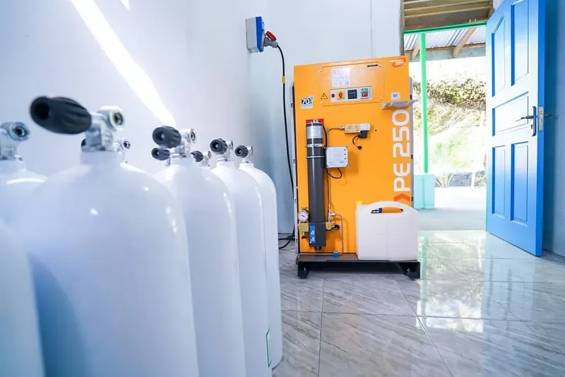 Bouteilles de plongée et compresseur orange dans un local lumineux