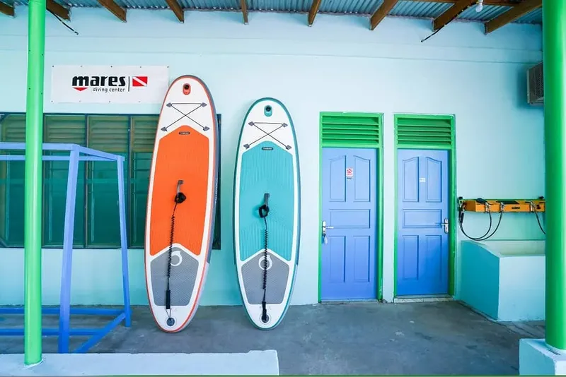 Deux planches de stand-up paddle adossées à un bâtiment bleu et orange