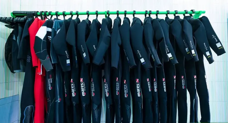 Rangée de combinaisons de plongée noires et rouges suspendues sur cintres