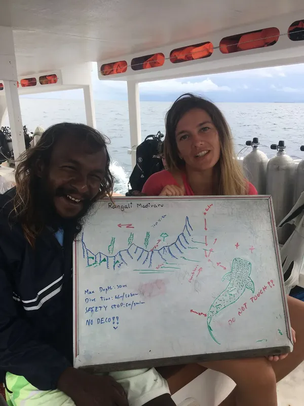 Deux plongeurs souriants présentent un schéma de site de plongée