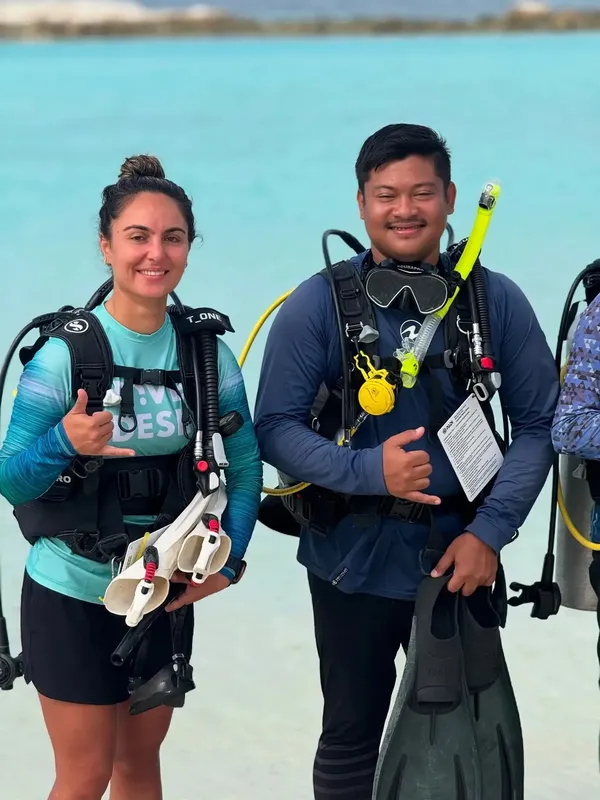 Deux plongeurs souriants équipés prêts pour une immersion en mer