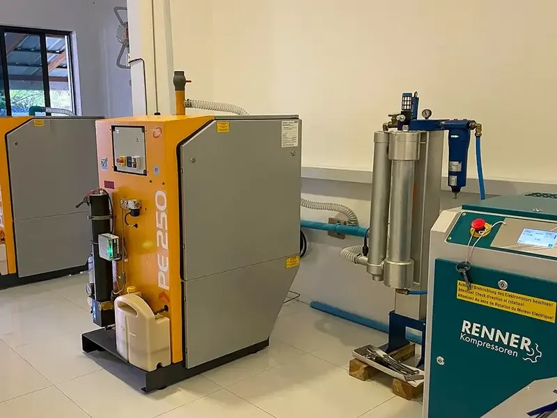 Compresseur de plongée industriel orange et turquoise dans un local technique