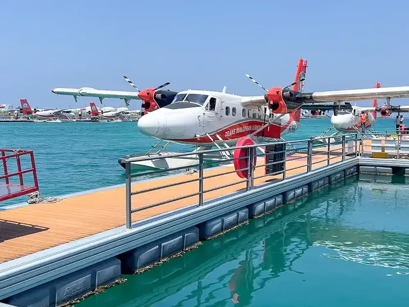 Hydravion amarré à un ponton flottant sur une eau turquoise claire