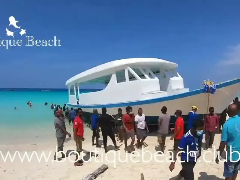 Groupe de personnes sur une plage devant un bateau de plongée