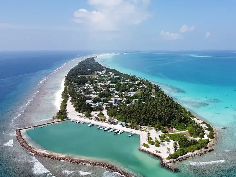 Île tropicale avec plage, végétation, bateaux et bâtiments colorés