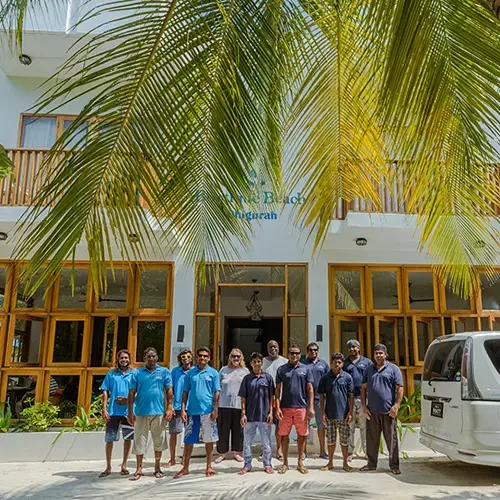 Groupe de personnes souriantes devant le bâtiment d'un centre de plongée tropical