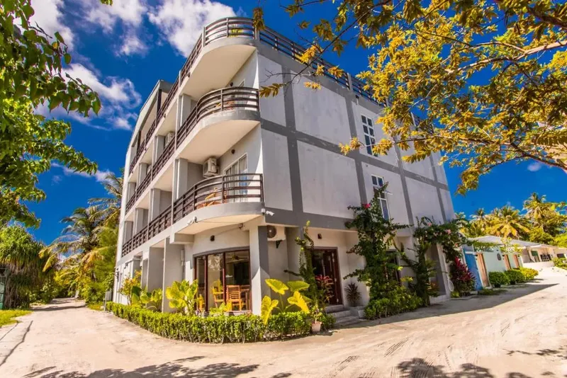 Bâtiment blanc à plusieurs étages avec végétation tropicale et ciel bleu