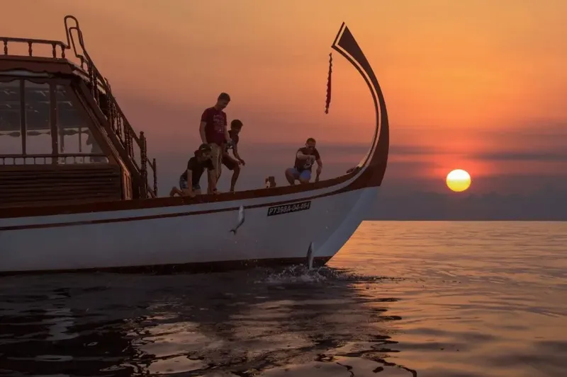 Personnes sur la proue d'un bateau au coucher du soleil en mer