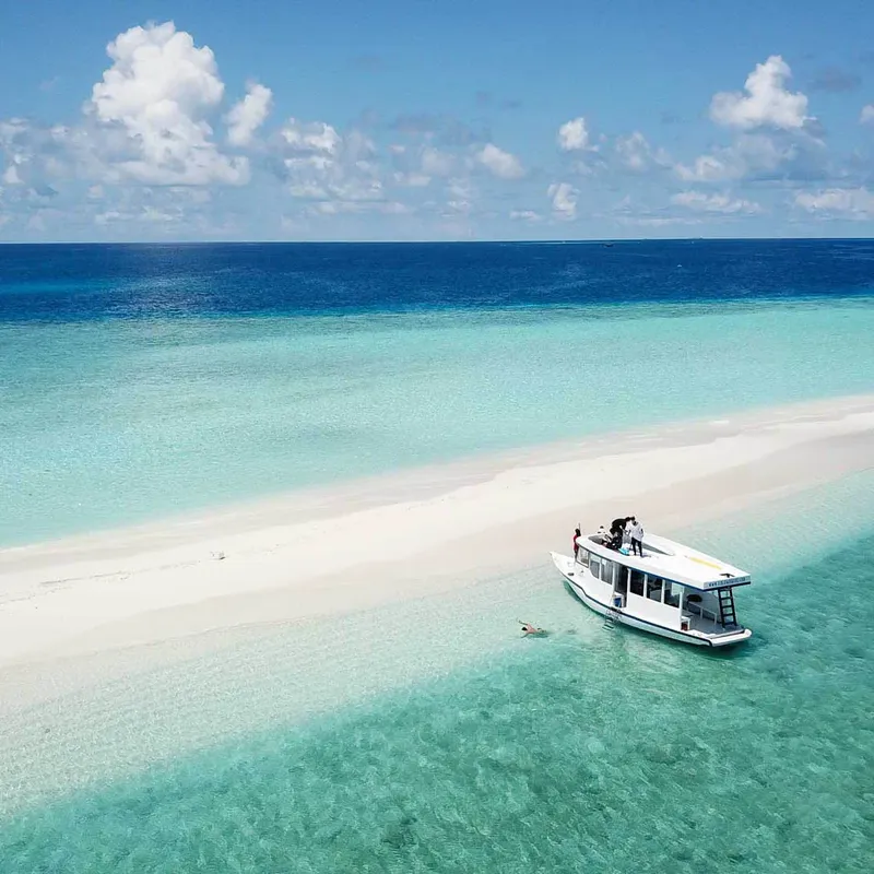 Bateau de plongée amarré près d'une plage de sable blanc turquoise