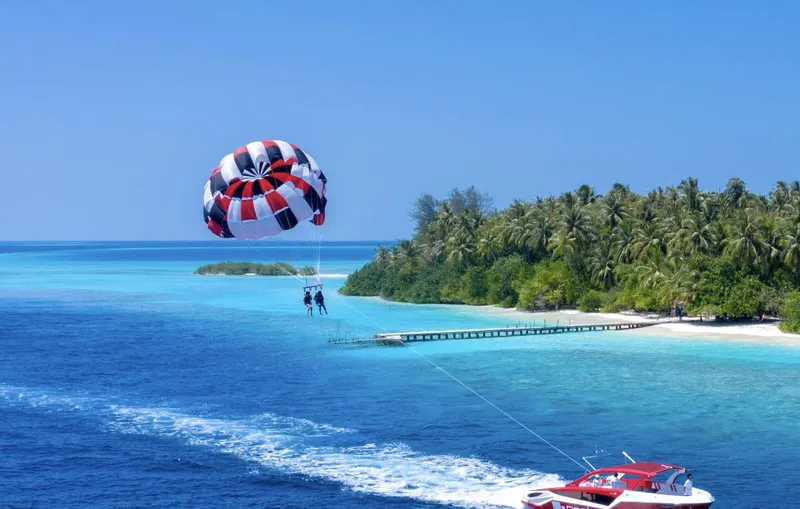 Personnes en parachute ascensionnel au-dessus d'une eau turquoise et d'une plage