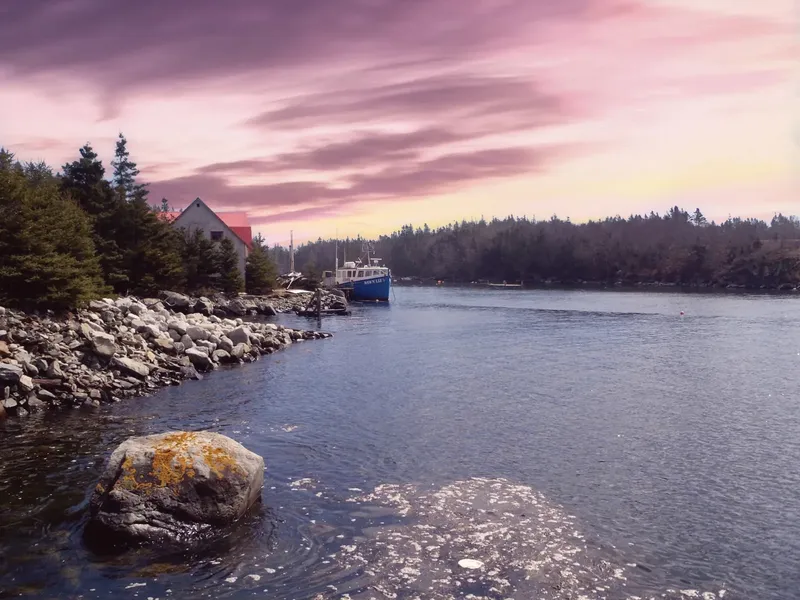 Bateau de plongée amarré dans une baie rocheuse au coucher du soleil