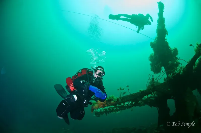 Deux plongeurs explorent une épave sous-marine dans une eau turquoise