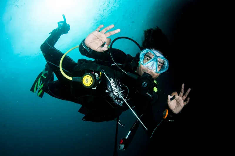 Plongeur souriant sous l'eau, faisant des signes de paix avec ses mains