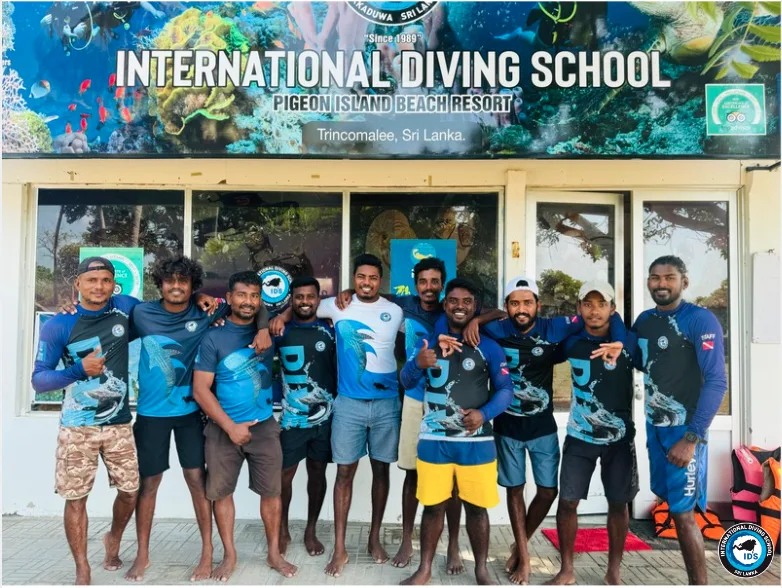 Groupe de personnes souriantes devant la facade d'une ecole de plongée