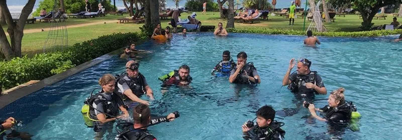 Groupe de plongeurs en formation dans une piscine, équipement complet visible