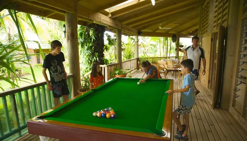 Enfants jouant au billard sur une terrasse couverte ensoleillée