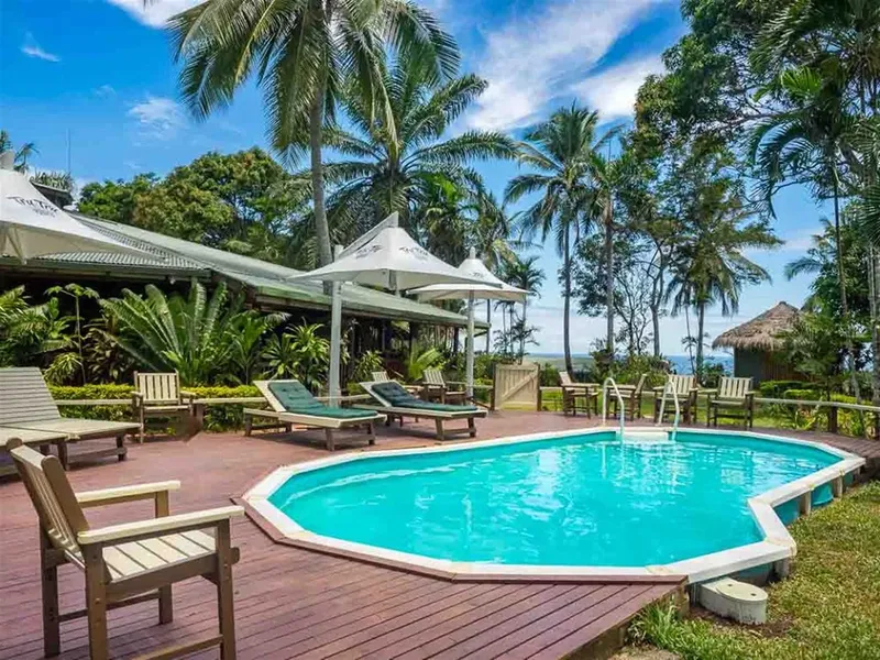 Piscine extérieure avec chaises longues et végétation tropicale luxuriante