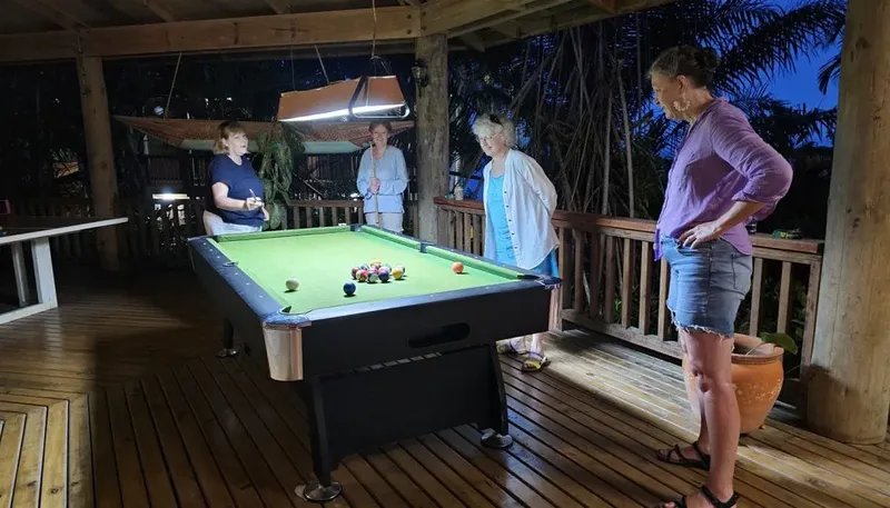 Quatre personnes jouant au billard dans un espace extérieur éclairé